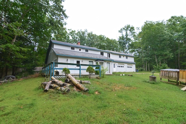 rear view of property with a garage and a yard