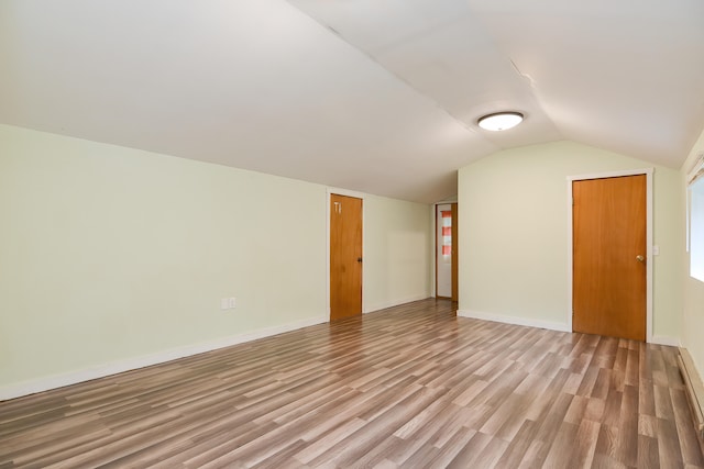 additional living space featuring vaulted ceiling and wood-type flooring