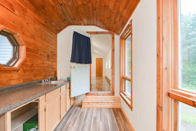 kitchen with light wood-type flooring, wood walls, sink, wooden ceiling, and vaulted ceiling