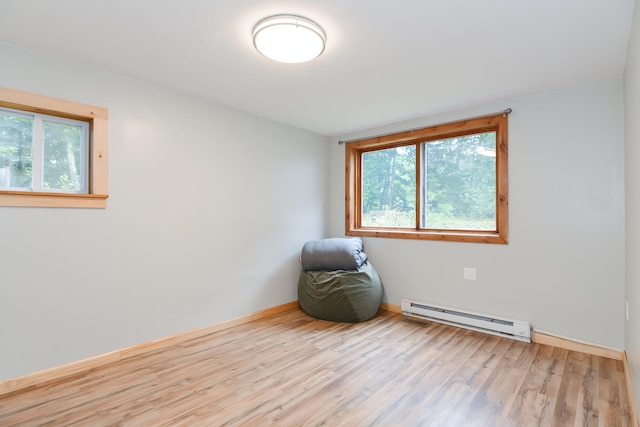 unfurnished room featuring a baseboard heating unit and light hardwood / wood-style floors