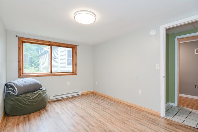 spare room with baseboard heating and light hardwood / wood-style flooring