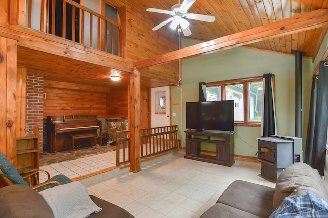 tiled living room with beamed ceiling, wooden ceiling, a wood stove, ceiling fan, and wooden walls