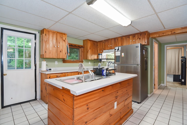 kitchen featuring light tile patterned floors, stainless steel refrigerator, sink, and a drop ceiling