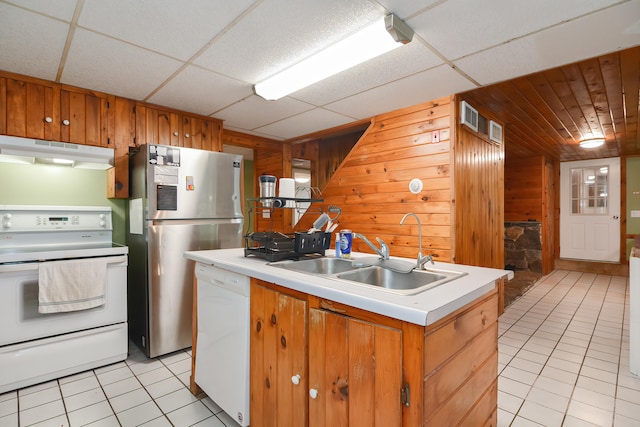 kitchen with a drop ceiling, white dishwasher, wooden walls, and range