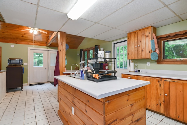 kitchen with ceiling fan, plenty of natural light, a drop ceiling, and light tile patterned flooring