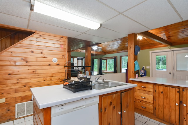 kitchen with dishwasher, a kitchen island with sink, light tile patterned flooring, and a drop ceiling