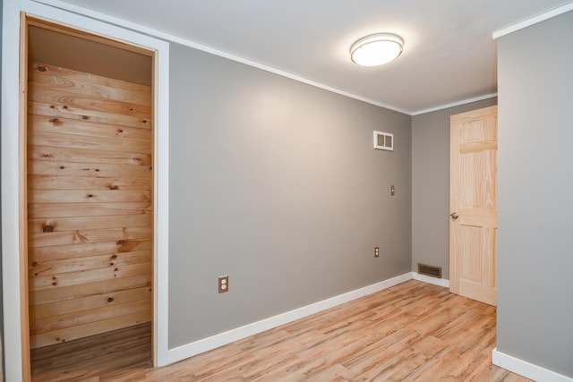 spare room featuring light wood-type flooring and crown molding