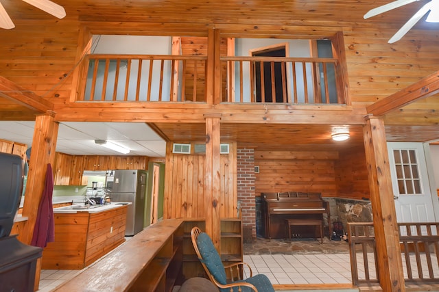 living room featuring tile patterned flooring, ceiling fan, and wooden walls