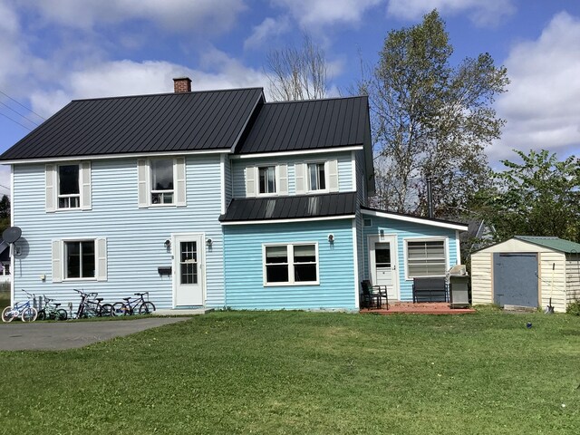 back of property with a lawn and a shed