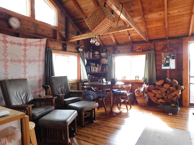 living area with vaulted ceiling with beams, wood ceiling, hardwood / wood-style floors, and a healthy amount of sunlight