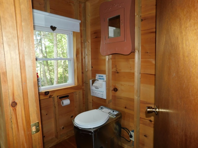 bathroom featuring wood walls and toilet