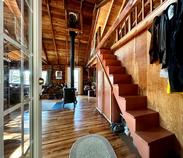 interior space with a wood stove, vaulted ceiling with beams, hardwood / wood-style flooring, and wooden walls