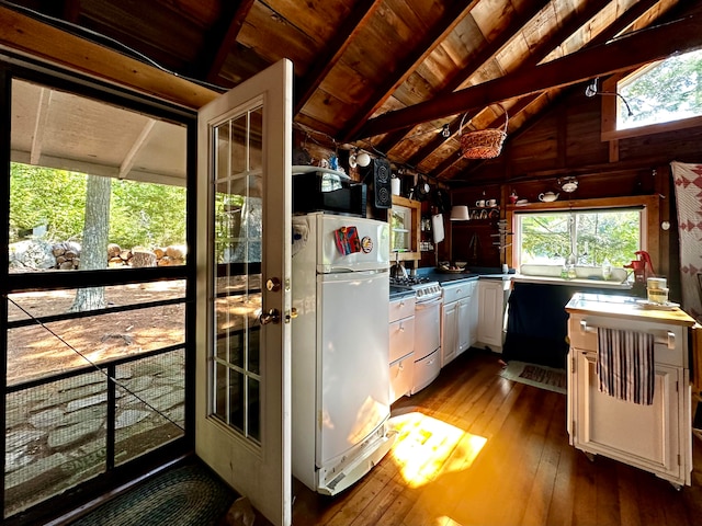 kitchen with vaulted ceiling with beams, white appliances, plenty of natural light, and dark hardwood / wood-style flooring