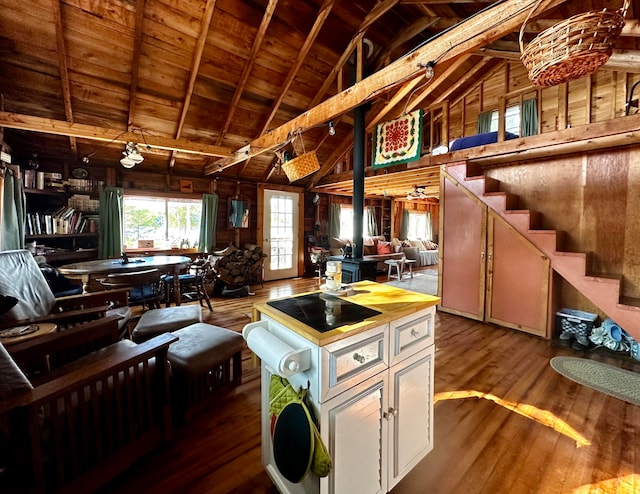 kitchen with lofted ceiling with beams, wood-type flooring, wooden walls, ceiling fan, and wooden ceiling