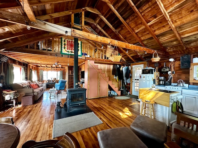 living room featuring wood ceiling, beam ceiling, a wood stove, wooden walls, and light wood-type flooring