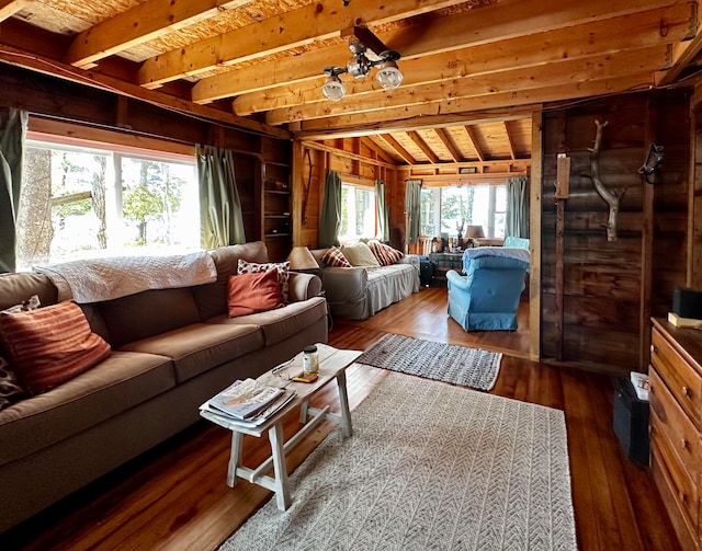 living room featuring vaulted ceiling with beams, a healthy amount of sunlight, wood walls, and hardwood / wood-style flooring