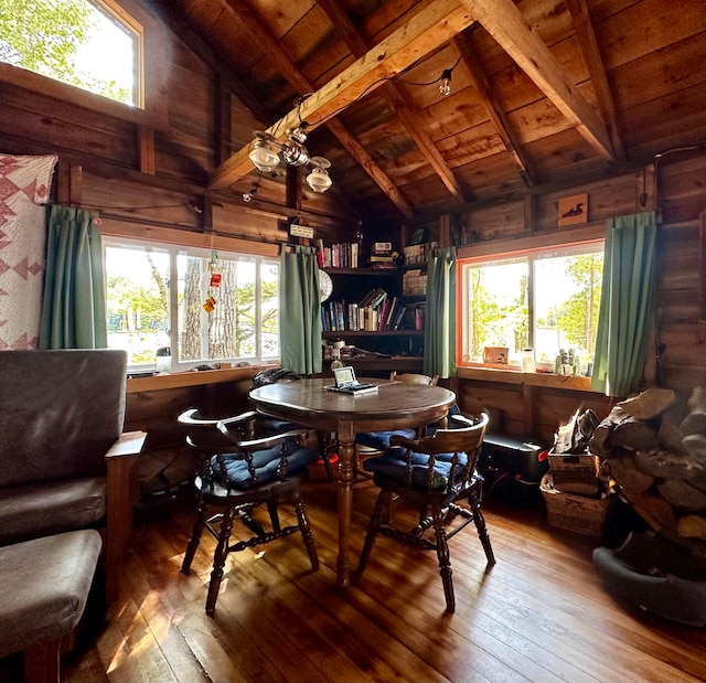 dining space featuring wooden ceiling, wood-type flooring, wood walls, and beamed ceiling