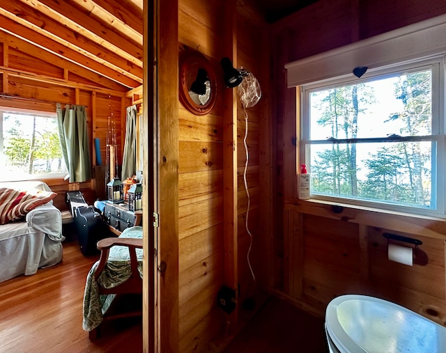 bathroom with a wealth of natural light, wood walls, vaulted ceiling, and hardwood / wood-style flooring