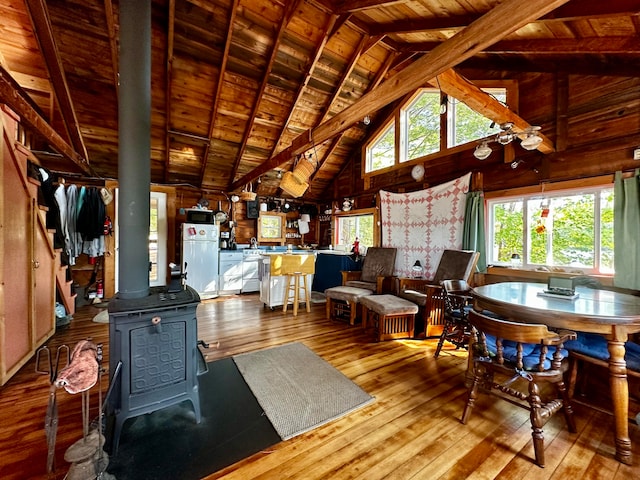 living room featuring high vaulted ceiling, beamed ceiling, a wood stove, wooden ceiling, and hardwood / wood-style floors