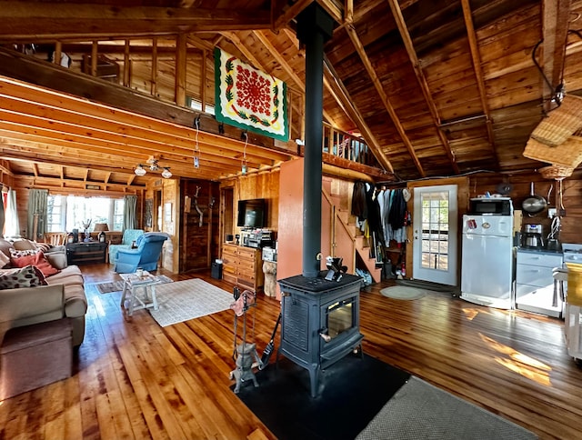 living room featuring beam ceiling, wood walls, hardwood / wood-style floors, and a wood stove