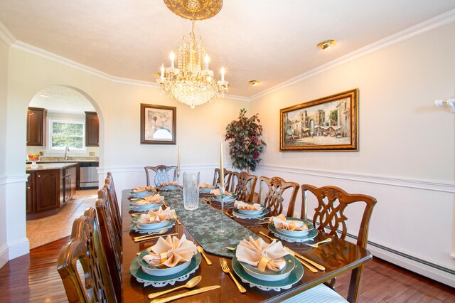 dining space featuring a notable chandelier, crown molding, baseboard heating, sink, and hardwood / wood-style flooring