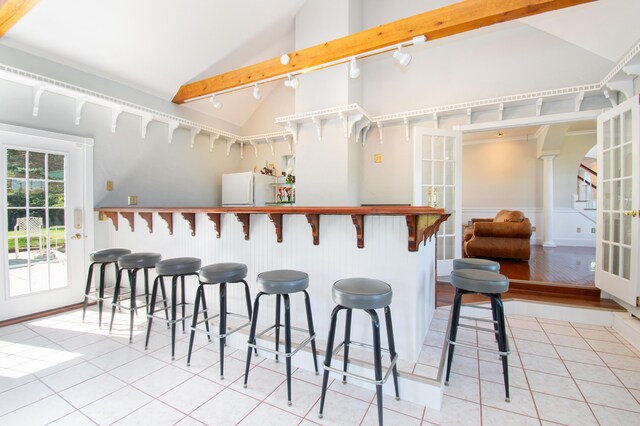 bar featuring french doors, light tile patterned flooring, white fridge, and lofted ceiling with beams