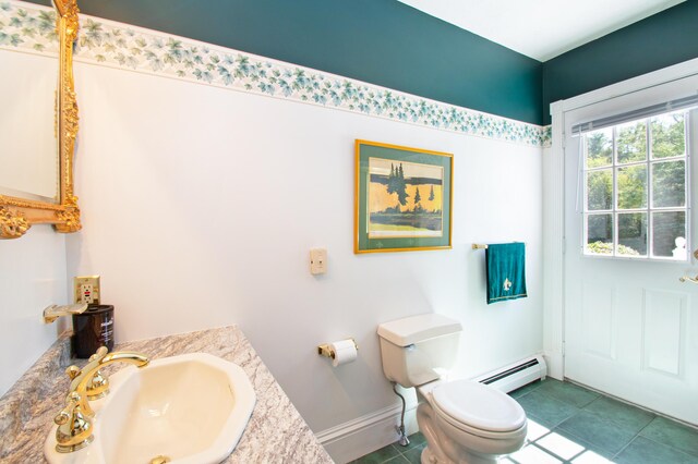 bathroom featuring a baseboard heating unit, a healthy amount of sunlight, toilet, and tile patterned flooring