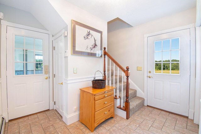 foyer featuring a baseboard heating unit and vaulted ceiling