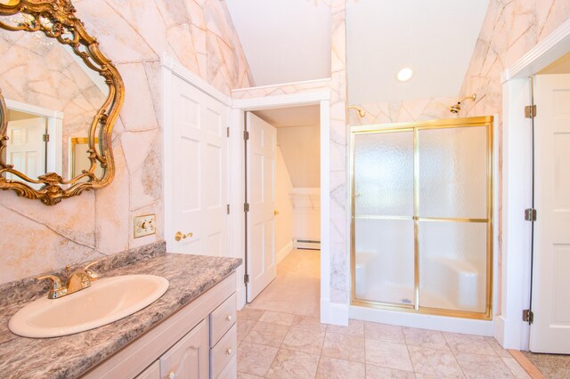 bathroom featuring a shower with shower door, baseboard heating, vanity, and tile walls