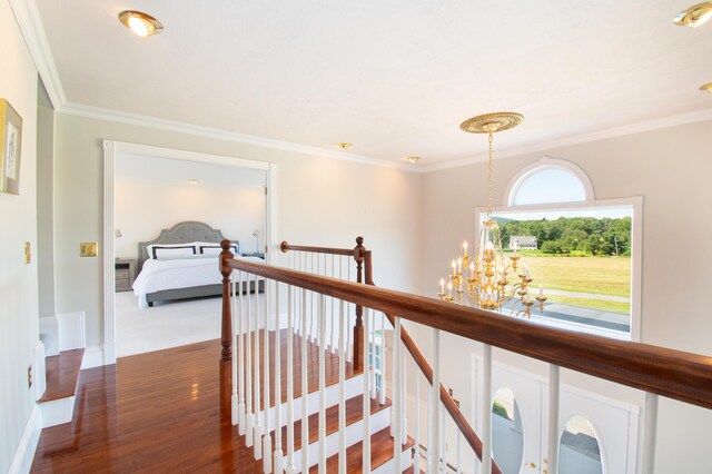 hallway featuring crown molding, hardwood / wood-style floors, and a chandelier