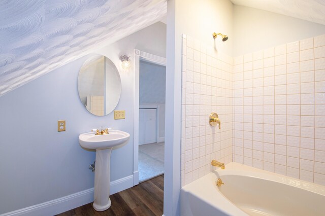 bathroom with tiled shower / bath combo, lofted ceiling, hardwood / wood-style floors, and a textured ceiling