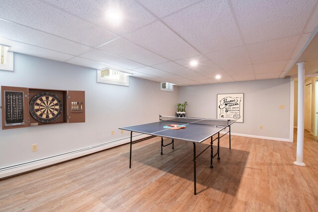 game room with a paneled ceiling, a baseboard radiator, and light hardwood / wood-style flooring