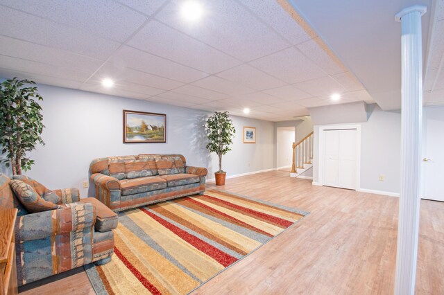 living room with a paneled ceiling, hardwood / wood-style floors, and ornate columns