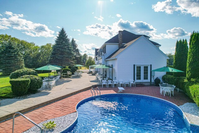 view of pool with french doors and a patio area