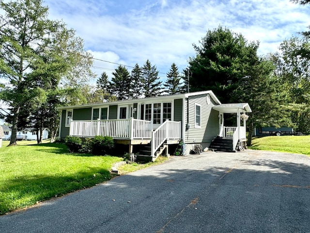 manufactured / mobile home with covered porch, a front yard, and aphalt driveway