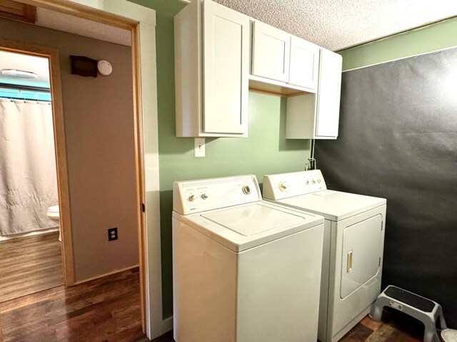 clothes washing area with a textured ceiling, dark hardwood / wood-style flooring, cabinets, and washer and dryer