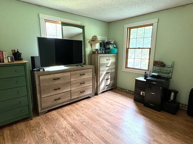 bedroom featuring a textured ceiling, light hardwood / wood-style flooring, and multiple windows