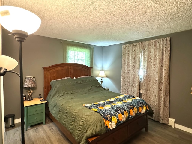 bedroom with a textured ceiling, baseboards, and wood finished floors