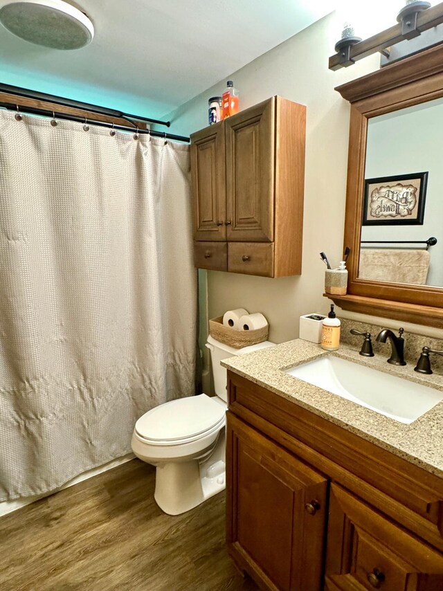 bathroom featuring curtained shower, hardwood / wood-style floors, toilet, and vanity