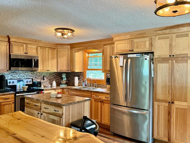 kitchen featuring a textured ceiling, a center island, sink, appliances with stainless steel finishes, and hardwood / wood-style flooring