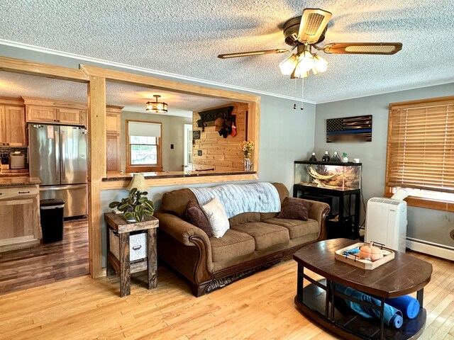 living room with light wood-type flooring, crown molding, a textured ceiling, and ceiling fan