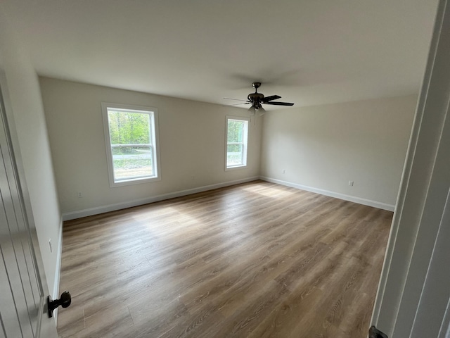 spare room featuring a ceiling fan, wood finished floors, and baseboards