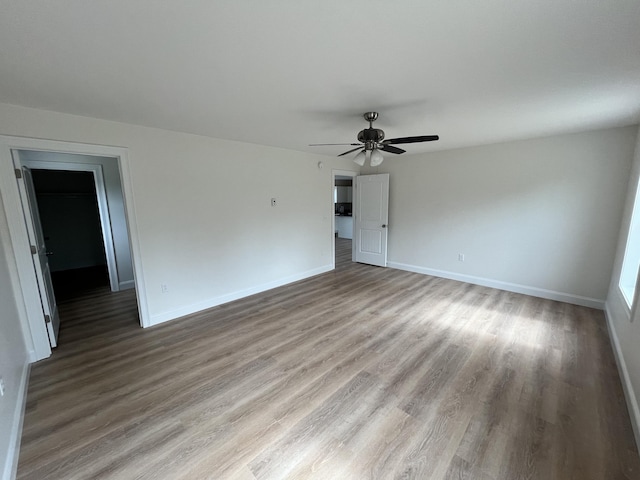 empty room featuring wood finished floors, baseboards, and a ceiling fan