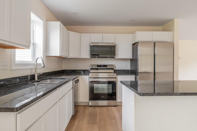 268 Merrill Rd, Levant, ME 04456 - kitchen featuring stainless steel appliances, a sink, white cabinets, light wood-style floors, and dark stone counters