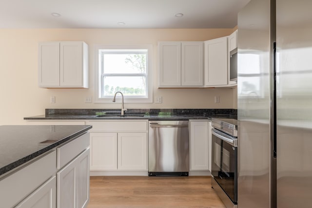 268 Merrill Rd, Levant, ME 04456 - kitchen with stainless steel appliances, a sink, dark stone countertops, white cabinets, and light wood-type flooring