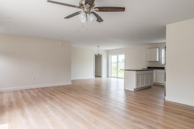 268 Merrill Rd, Levant, ME 04456 - unfurnished living room with light wood finished floors, baseboards, ceiling fan, and a chandelier