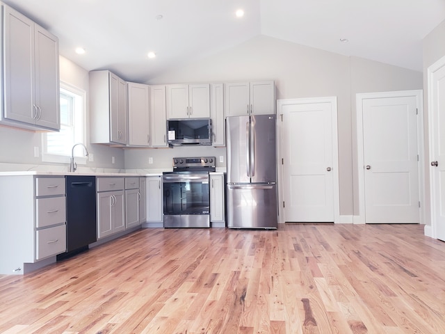 kitchen featuring light hardwood / wood-style flooring, stainless steel appliances, gray cabinetry, and vaulted ceiling