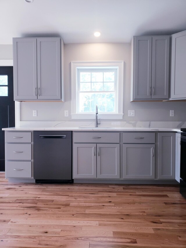 kitchen featuring light hardwood / wood-style flooring, gray cabinetry, sink, and stainless steel dishwasher