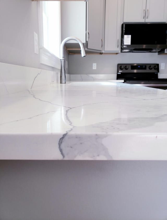 kitchen featuring light stone countertops, appliances with stainless steel finishes, and white cabinetry