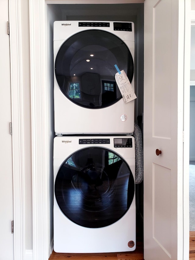 clothes washing area with stacked washer and dryer and hardwood / wood-style flooring